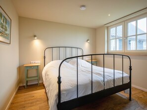 A bedroom with a single bed, a small bedside table, a nightstand, a window with a view, and a ceiling light. - Holiday Home With 2 Bedrooms (Den Hoorn)