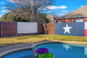 Ein Garten mit Swimmingpool, Schwimmreifen, Holzzaun und einem Haus mit Sternenverzierungen.