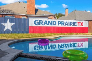 Ein Schwimmbecken mit einem Zaun, der mit 'GRAND PRAIRIE TX' und einem Stern bemalt ist.