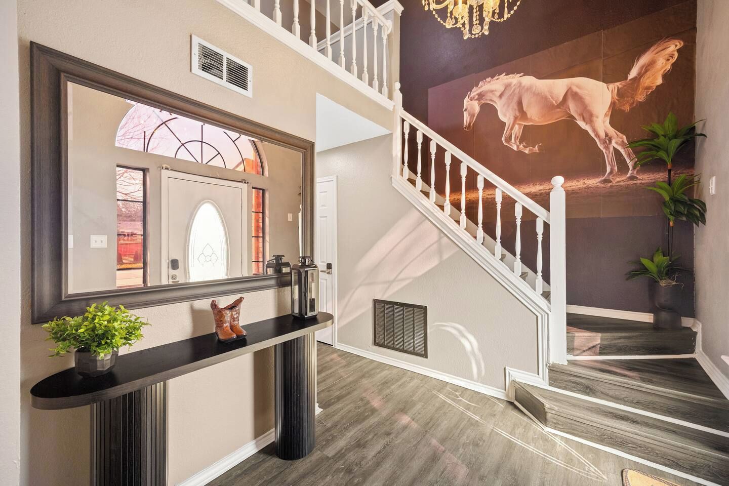A staircase with a horse mural, a reception desk with a plant, and a door with a glass panel.