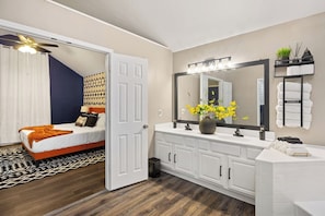 Ein Schlafzimmer mit einem Bett, einem Badezimmer mit Schminktisch und einem Deckenventilator.