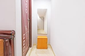 Un pasillo con una puerta de madera, un armario pequeño de madera y un espejo en la pared.