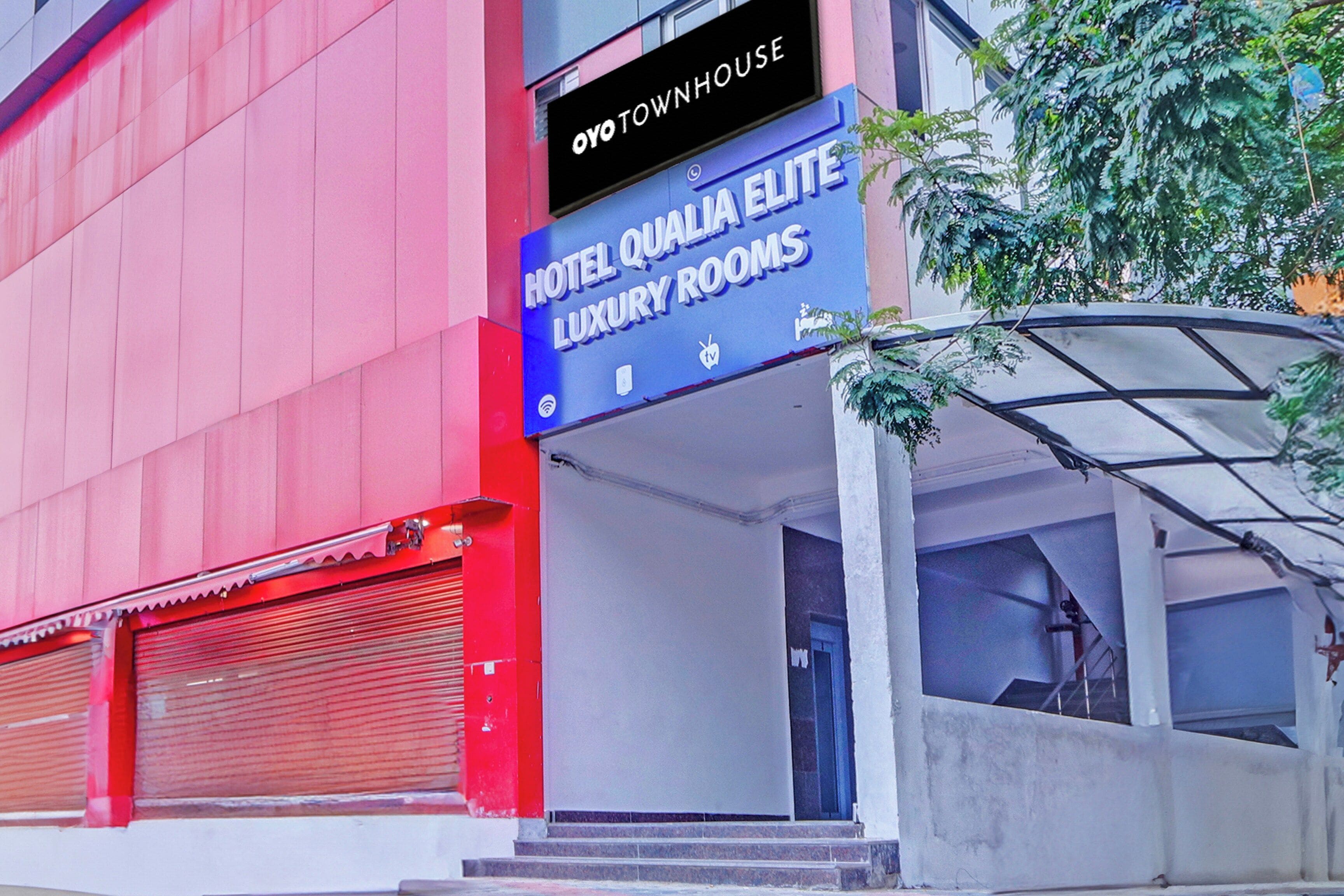 Une enseigne d’hôtel indiquant « Hôtel, chambres de luxe de qualité », avec une façade rouge et un volet fermé.