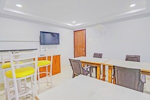 A conference room with a long table, chairs, a television, and a door. - Townhouse QUALIA ELITE S R NAGAR (Hyderabad)