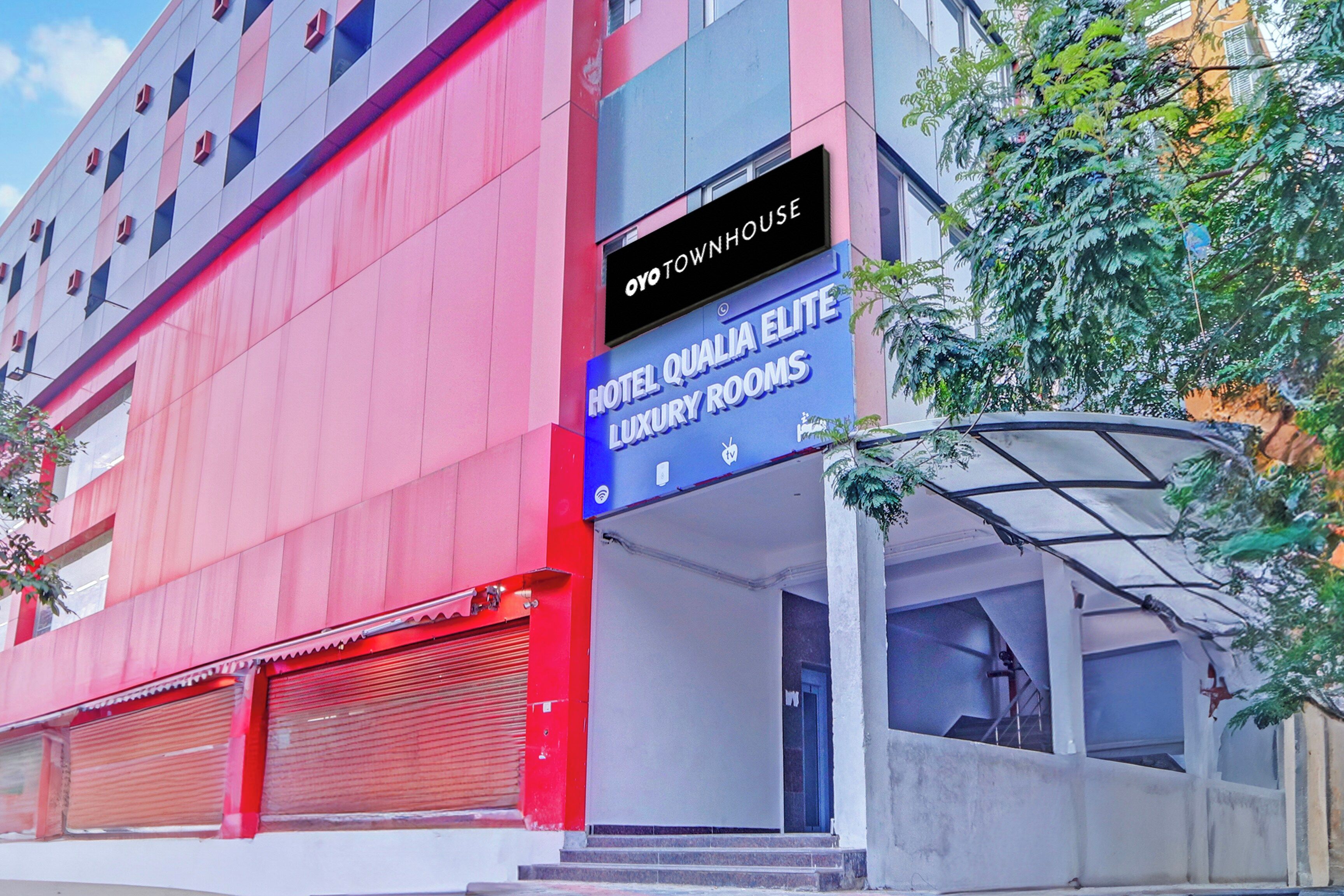 A hotel building with a sign indicating 'Hotel Qualia Elite Luxury Rooms' and 'Oyo Townhouse'.