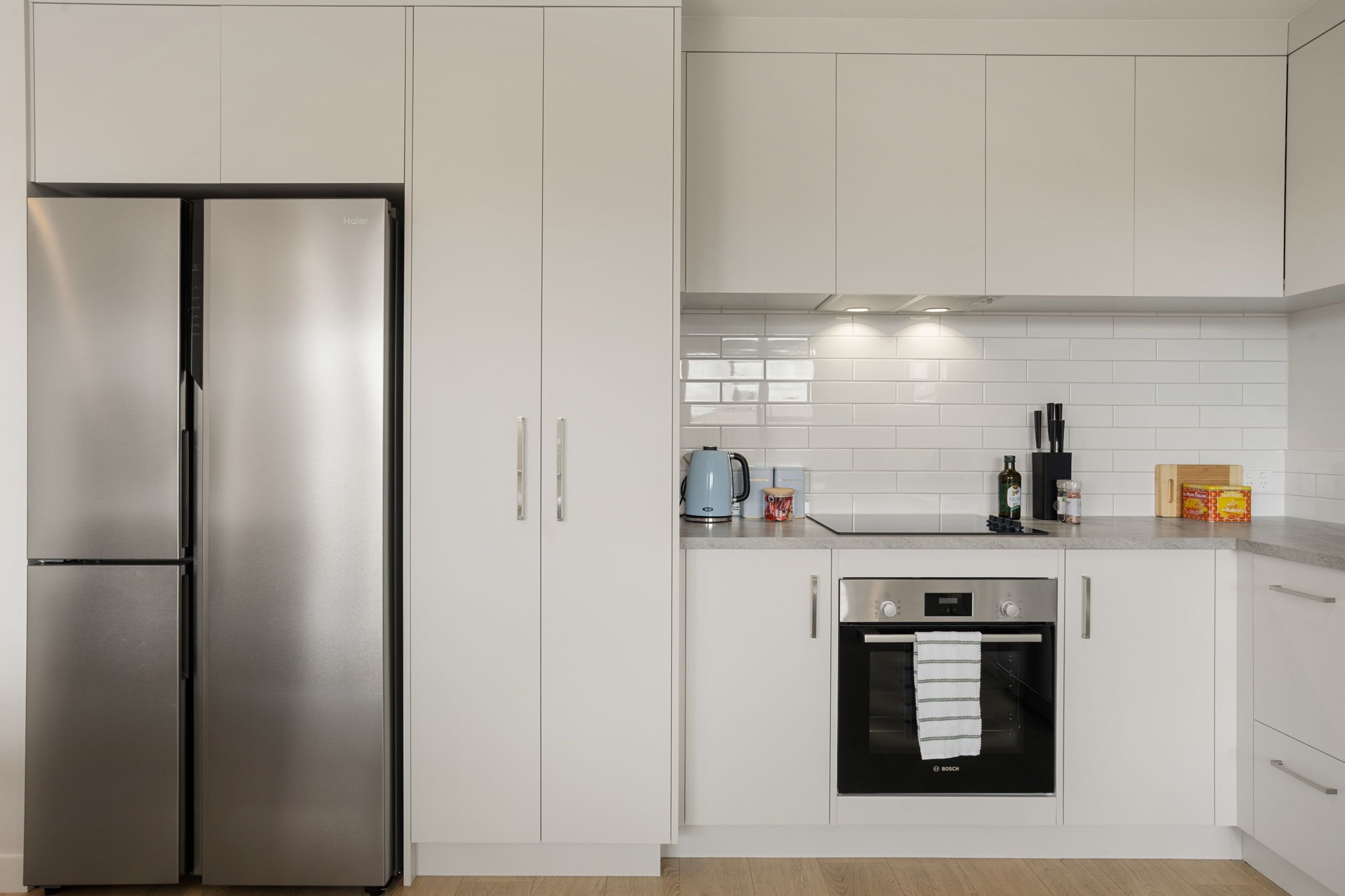 Een moderne keuken met een roestvrijstalen koelkast, een Bosch oven en witte keukenkastjes.
