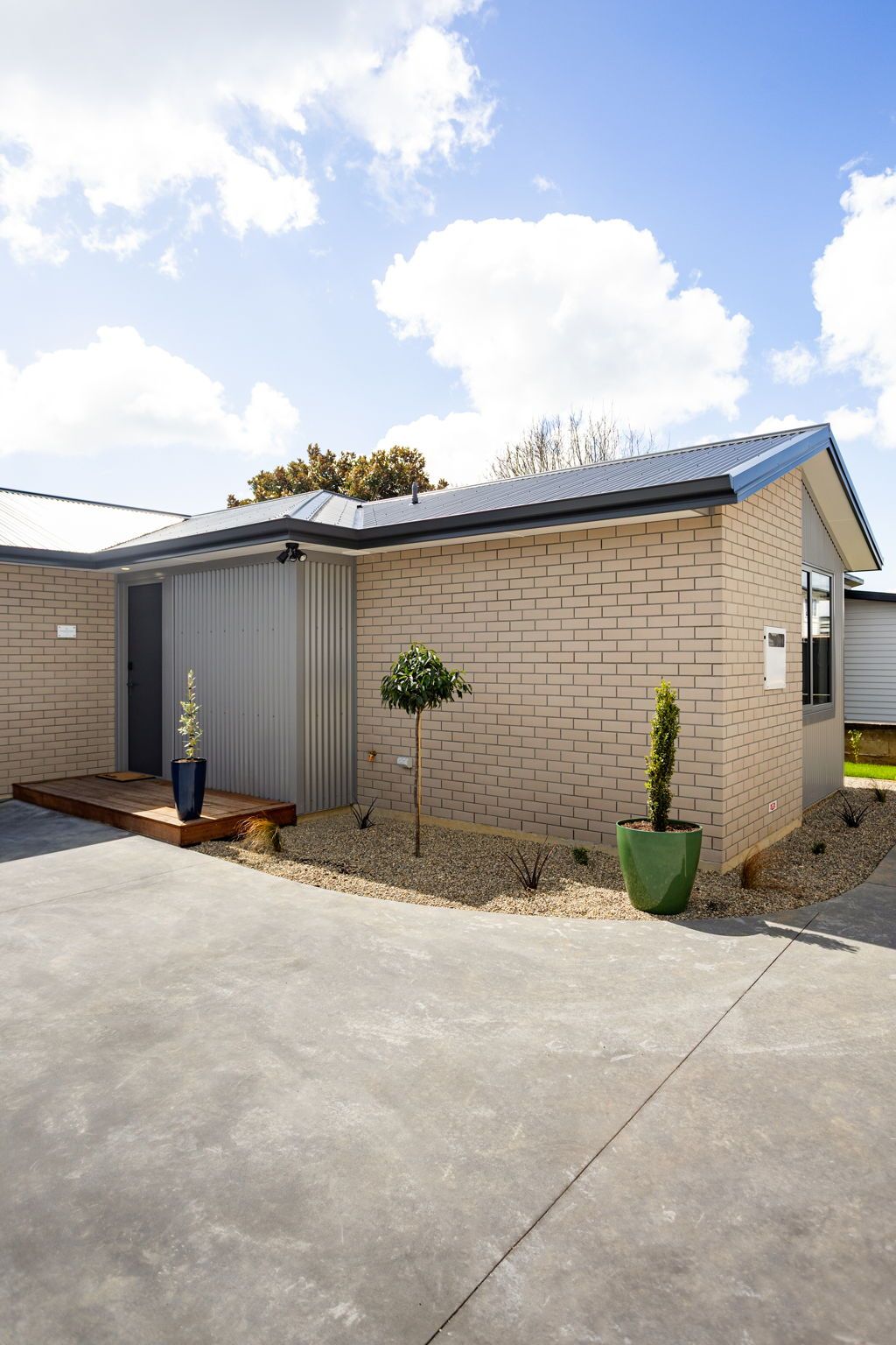Een laag gebouw met plat dak, garagepoort en klein voortuintje.