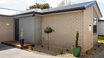 Een laag gebouw met plat dak, garagepoort en klein voortuintje.