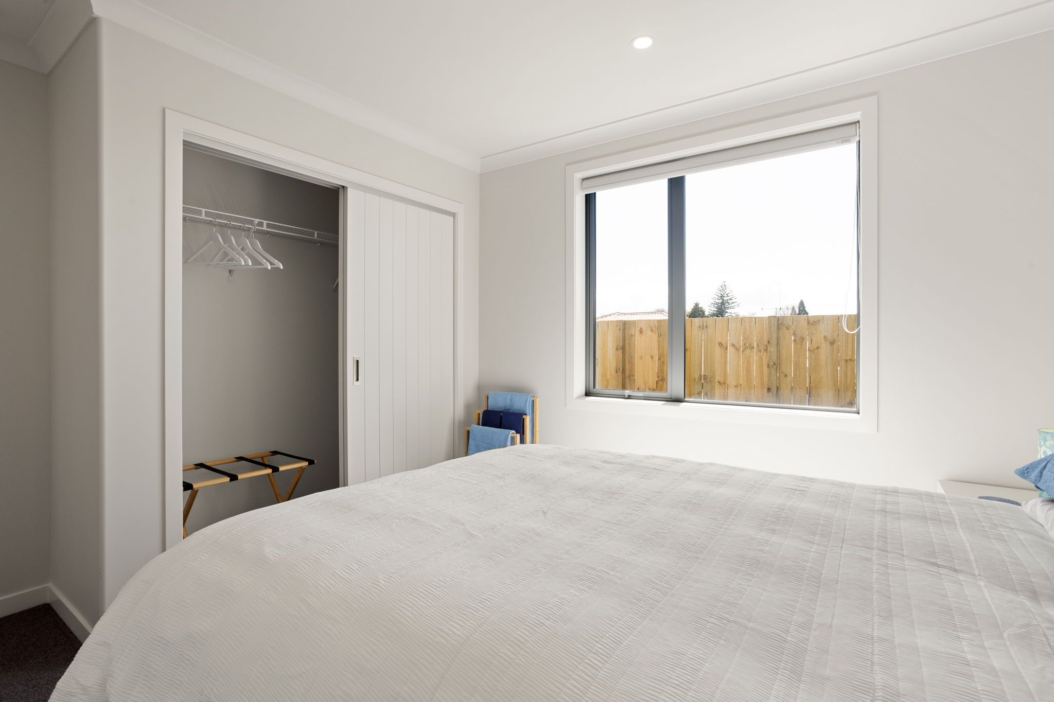 Un dormitorio con una cama grande, un armario, una silla y una ventana.