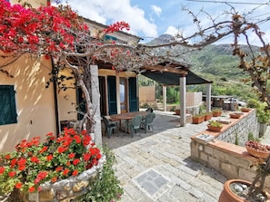 A patio with a table and chairs, surrounded by potted plants and a pergola. - Holiday Home With 2 Bedrooms (Marciana)