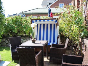 An outdoor seating area with wicker chairs and a striped tablecloth. - Holiday Apartment in Sylt With 2 Bedrooms (Sylt)