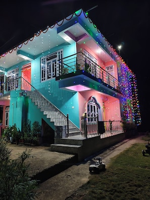 A two-story building with a staircase and a balcony, decorated with colorful lights.