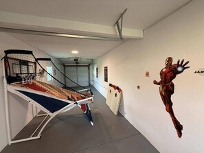 A hallway with a basketball hoop, a wall-mounted Iron Man statue, and a door with a logo. - Lovely Modern POOL home. 13 mins to the Beach! (Melbourne)