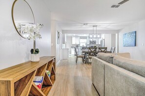 A modern living room with a wooden console table, a sofa, and a dining area with a table and chairs. - Lovely Modern POOL home. 13 mins to the Beach! (Melbourne)