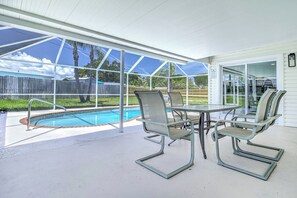 Un patio techado con piscina, mobiliario exterior y vista al jardín.