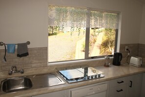 A kitchen with a window, a coffee maker, a toaster, and a sink. - Cozy Stay on Coast to Coast (Kaikohe)