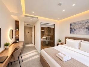 A modern hotel room with a bed, desk, chair, and a large painting on the wall. - SUNDAY BOUTIQUE PHU QUOC HOTEL (Phu Quoc)