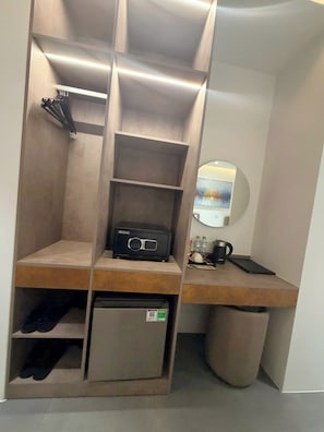 A compact room with a built-in desk, a small refrigerator, a trash bin, and a mirror. - SUNDAY BOUTIQUE PHU QUOC HOTEL (Phu Quoc)