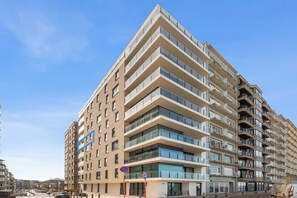 A multi-story hotel with a modern architectural design, featuring balconies on each floor and a clear view of the sky. - 2-bedroom Zeedijk Apartment (Blankenberge)