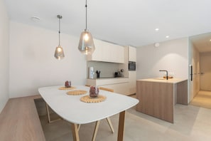 A modern kitchen with a white countertop, two pendant lights, and a central island with a sink. - 2-bedroom Zeedijk Apartment (Blankenberge)