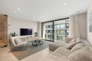 A modern living room with a large sofa, a coffee table, and a flat-screen TV. - 2-bedroom Zeedijk Apartment (Blankenberge)