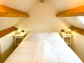 Ein Schlafzimmer mit einem Bett, zwei Nachttischen mit Lampen und einem Dachfenster.