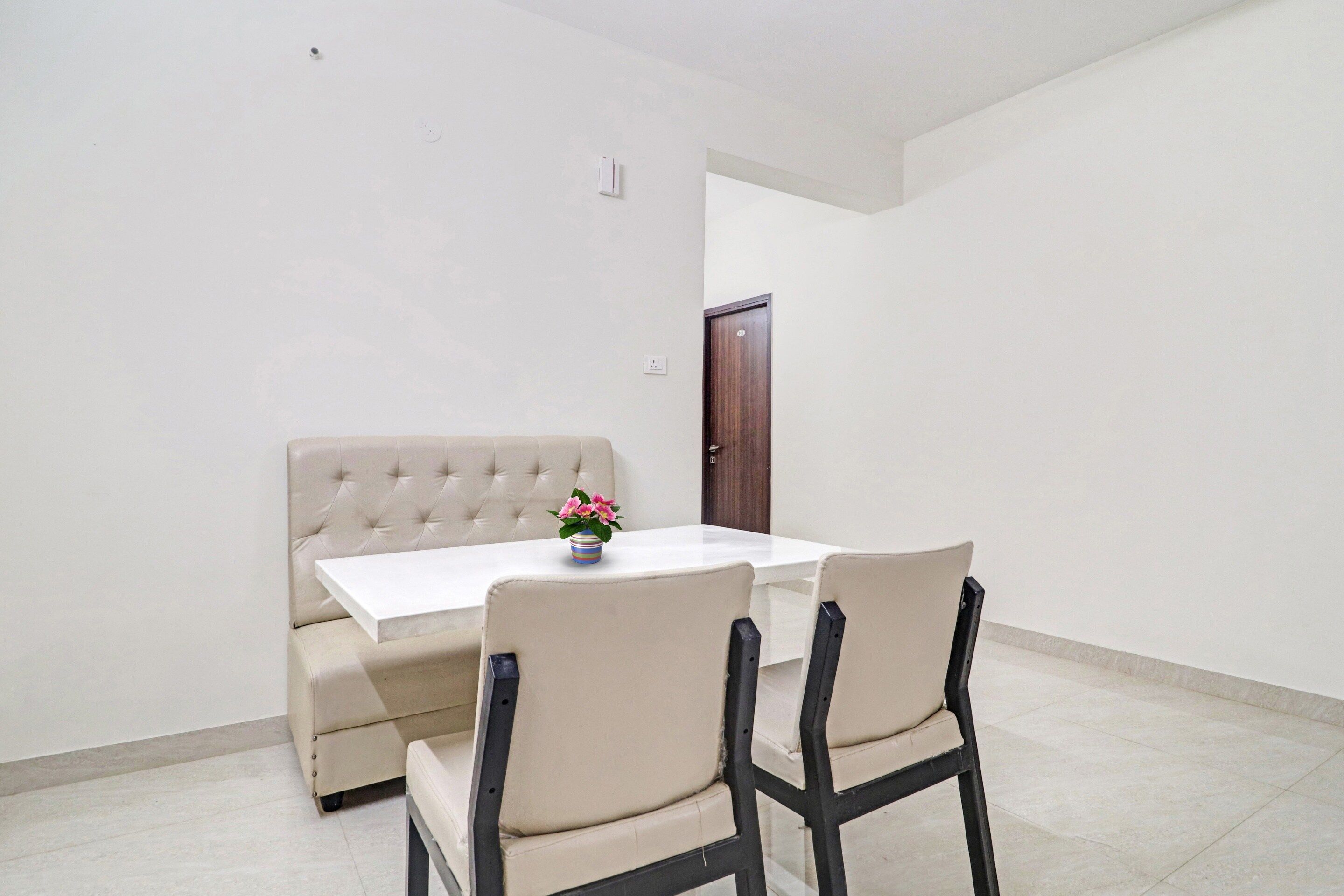 Un coin repas avec une table blanche, un canapé beige et deux chaises.