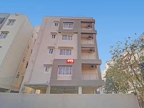 Un edificio de varios pisos con balcones y unidades de aire acondicionado.
