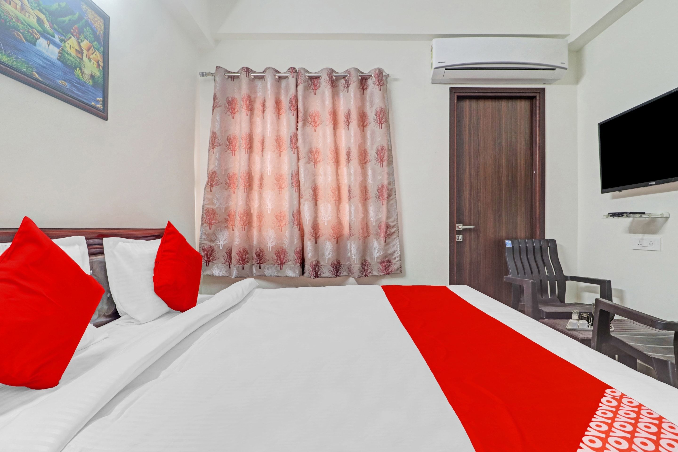 Een hotelkamer met een bed, een televisie, een bureau en een stoel.