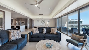 A modern living room with a sofa set, a coffee table, and a view of the city through large windows. - Two 1507: Luxury Above the Sea Of Cortez (Puerto Peñasco)