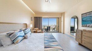 A hotel room with a large bed, a desk, a chair, a dresser, and a balcony with a view. - Two 1507: Luxury Above the Sea Of Cortez (Puerto Peñasco)