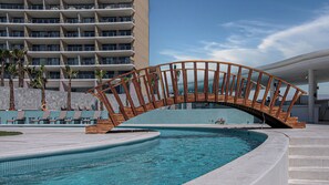 A swimming pool with a wooden bridge, lounge chairs, and a modern building in the background. - Two 1507: Luxury Above the Sea Of Cortez (Puerto Peñasco)
