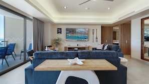 Un salon moderne avec un grand canapé, une table basse en bois et une vue sur une piscine, visible à travers de grandes fenêtres.