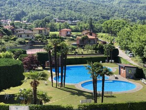 Ein Wohngebiet mit Swimmingpool, umgeben von Palmen und gepflegten Rasenflächen.