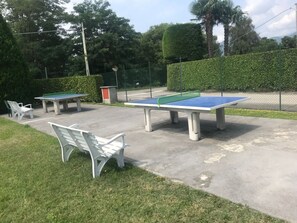 Tische für Tischtennis und Bänke in einer Parkanlage.