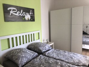 Ein Schlafzimmer mit Bett, Kissen, einem Nachttisch, einer Lampe und einer Wanddekoration.