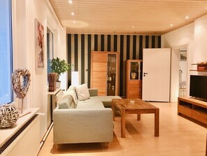 Ein modernes Wohnzimmer mit einer Couch, einem Holztisch und einem Fernseher.