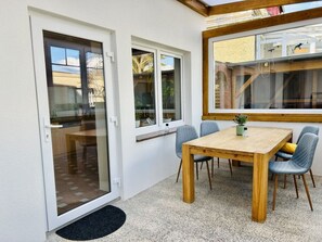 Ein Essbereich mit Holztisch und -stühlen, einer Schiebetür aus Glas und einem Fenster mit Außenblick.