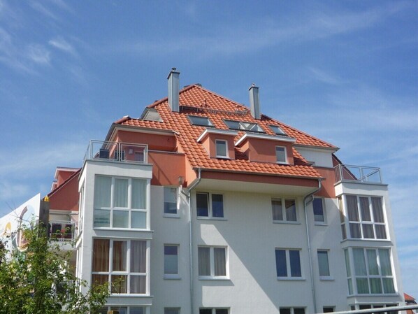 A multi-story residential building with a red-tiled roof, multiple balconies, and large windows. - Holiday Apartment With 3 Bedrooms (Grossenbrode)