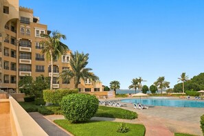 A hotel with a swimming pool, palm trees, and a clear sky. - Cozy Newly Full Renovated 1-bedroom Apartment With Full Seaviews From Every Room (Ras Al Khaimah)