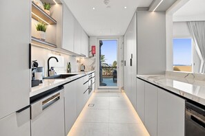 A modern kitchen with a central island, built-in appliances, and a view to the outside. - Cozy Newly Full Renovated 1-bedroom Apartment With Full Seaviews From Every Room (Ras Al Khaimah)