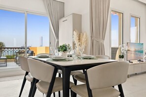 A dining area with a table set for four, large windows, and a view of the cityscape. - Cozy Newly Full Renovated 1-bedroom Apartment With Full Seaviews From Every Room (Ras Al Khaimah)