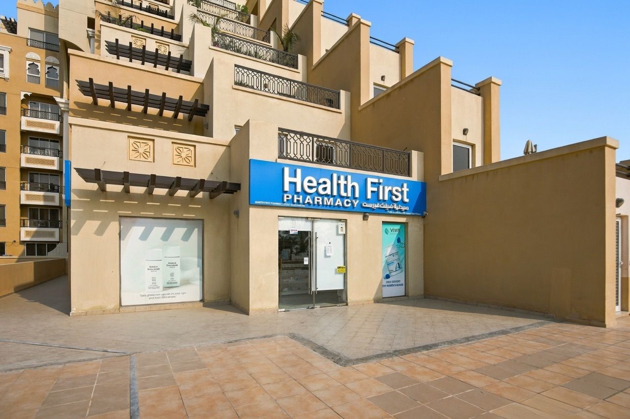 Ein Gebäude mit einem Schild, auf dem 'Health First Pharmacy' steht, und einer großen Werbung für Viva.