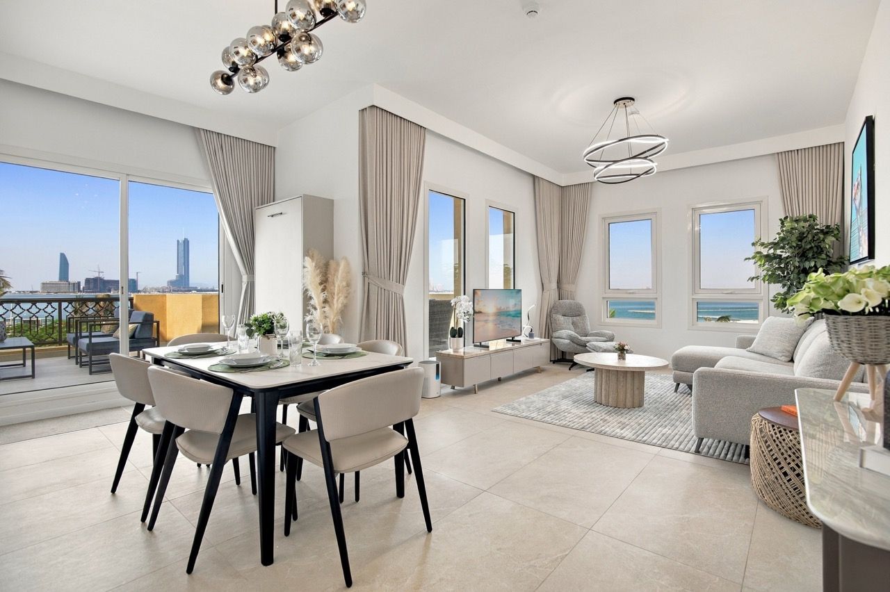 A modern living room with a dining area, large windows, and a view of the cityscape.
