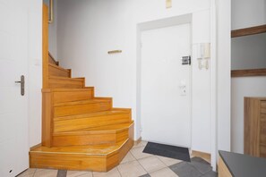 A staircase leading to a door with a light switch and a wall-mounted telephone. - Warsaw | Solidarności Avenue 92 | Two-storey Apartment | Balcony (Warszawa)