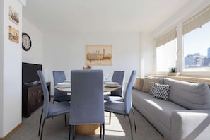 Ein moderner Wohnraum mit Essbereich, einer Couch und einem Fenster mit Blick auf die Stadt.