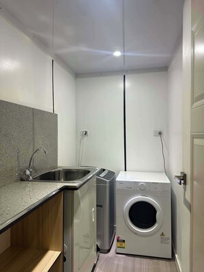 Een kleine wasruimte met een wasmachine, een droger en een wasbak.