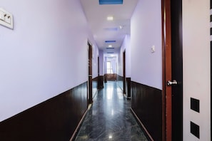 A corridor with doors on both sides, a marble floor, and a ceiling with recessed lighting. - Hotel O Qualia Grand (Hyderabad)