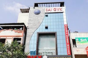 A hotel with a prominent 'SAI GVK' sign, a 'RAGAVA GUEST HOUSE' sign, and a 'REAL HYDERABADI BIRYANI' sign. - Hotel O Qualia Grand (Hyderabad)