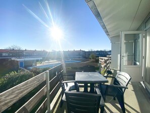 A balcony with a table and chairs, overlooking a swimming pool and buildings. - Holiday Apartment in Westkapelle With Wi-fi (Westkapelle)